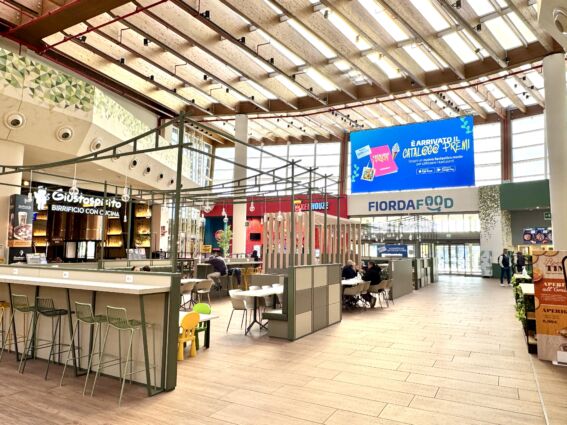 Food court affollata. Ristoranti, tavoli e sedie. Schermo digitale. Food service.