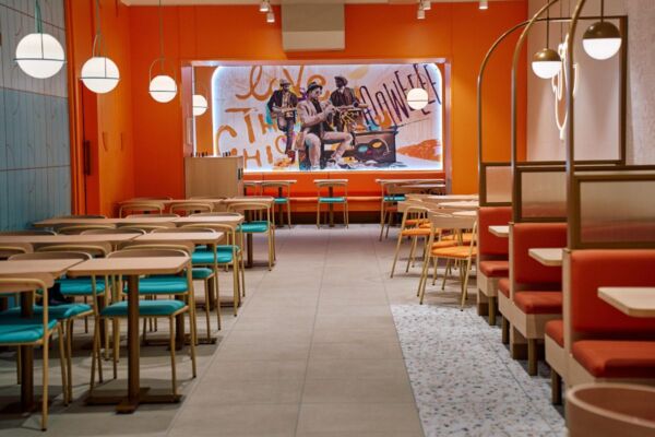 Interno del ristorante Popeyes a Torino. Arredamento colorato, tavoli e divanetti. Pollo fritto della Louisiana.