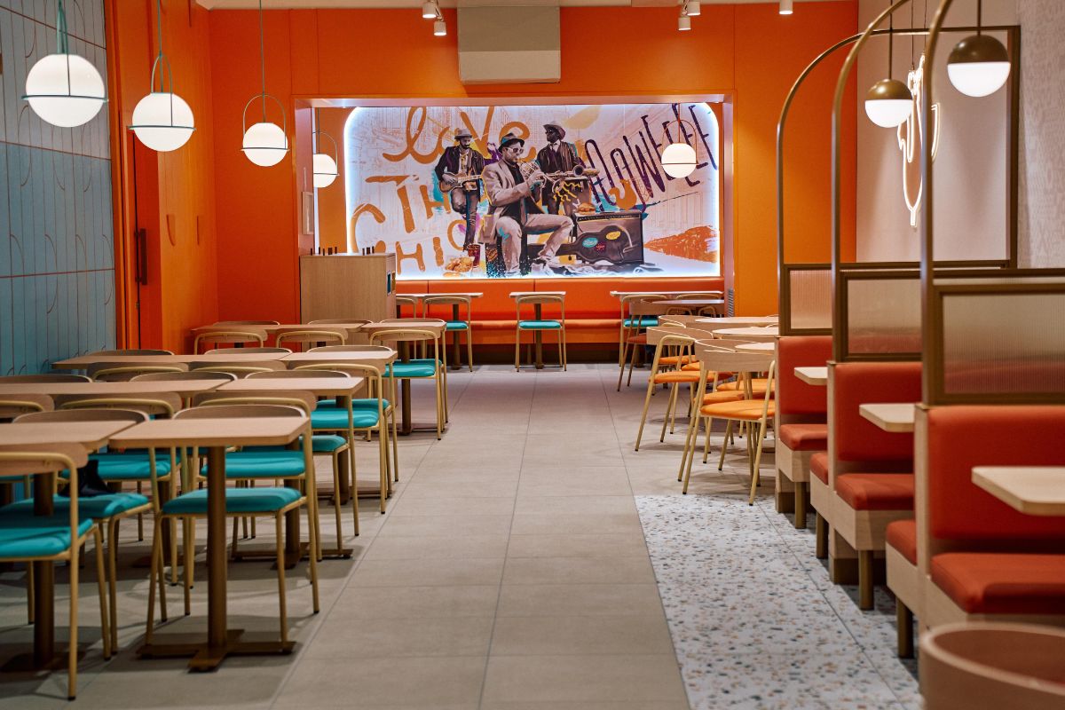 Interno del ristorante Popeyes a Torino. Arredamento colorato, tavoli e divanetti. Pollo fritto della Louisiana.