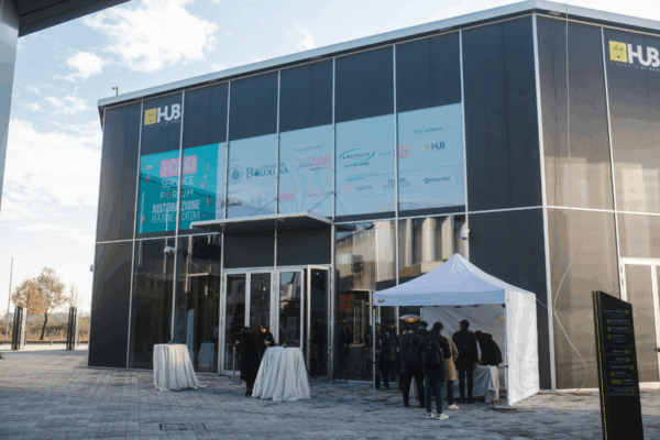 Ingresso al Food Service Forum: evento sulla ristorazione italiana. Persone in fila, stand e loghi di sponsor.