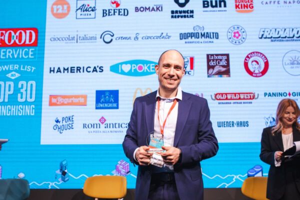 Premiazione Food Service Powerlist: top 30 franchising. Uomo sorridente con premio. Ristorazione e successo.