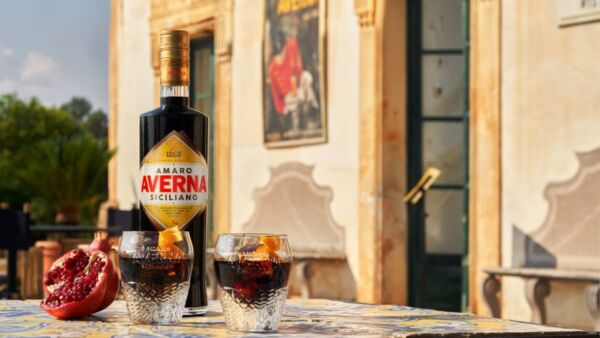 Bottiglia e bicchieri di Amaro Averna. Aperitivo siciliano con melograno.