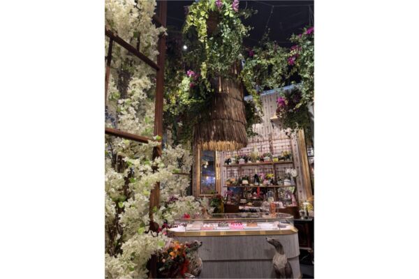 Design natura per spazi commerciali: fiori bianchi, verde pensile e bancone elegante.