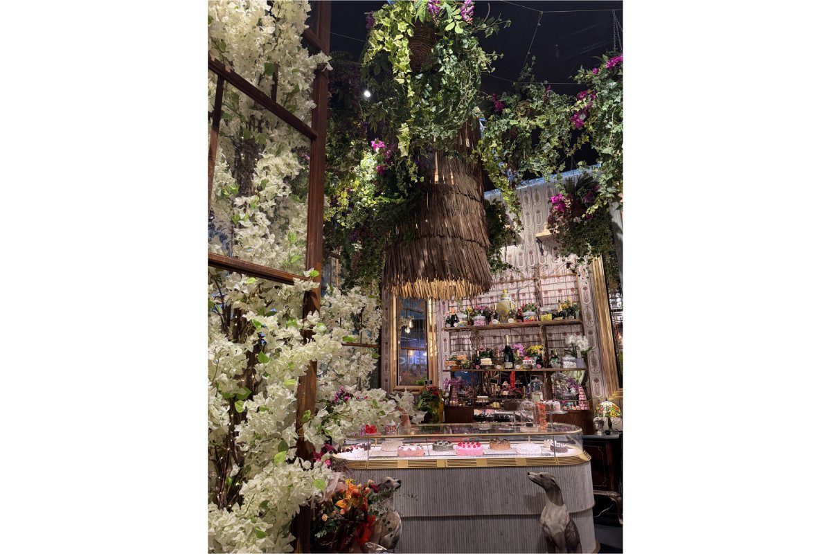 Design natura per spazi commerciali: fiori bianchi, verde pensile e bancone elegante.