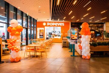 Interno del ristorante Popeyes all'ELNÒS Shopping di Brescia, con tavoli, sedie e decorazioni di palloncini.