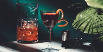 Cocktail elegante per ristorazione. Bicchiere con scorza d'arancia, ghiaccio. Savills food report.
