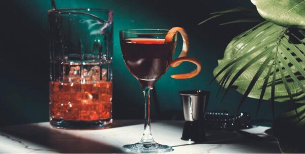 Cocktail elegante per ristorazione. Bicchiere con scorza d'arancia, ghiaccio. Savills food report.