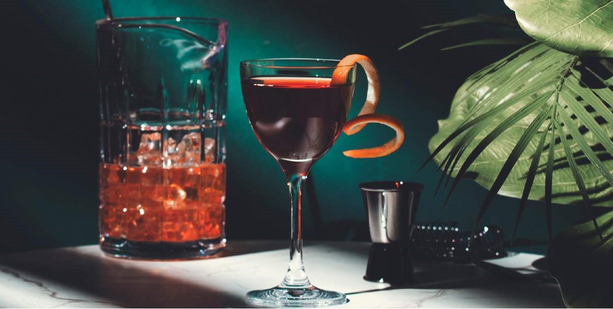 Cocktail elegante per ristorazione. Bicchiere con scorza d'arancia, ghiaccio. Savills food report.