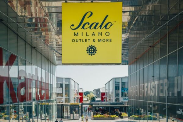 Scalo Milano Outlet & More: vista esterna del centro commerciale con insegna gialla. Shopping a Milano.