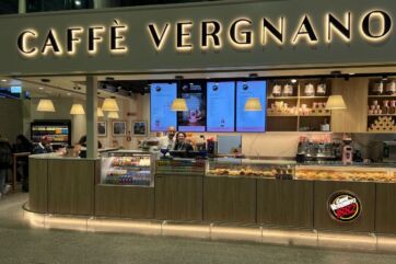 Caffè Vergnano a Fiumicino. Bar con insegna luminosa, bancone con dolci e bevande. Women in Coffee.
