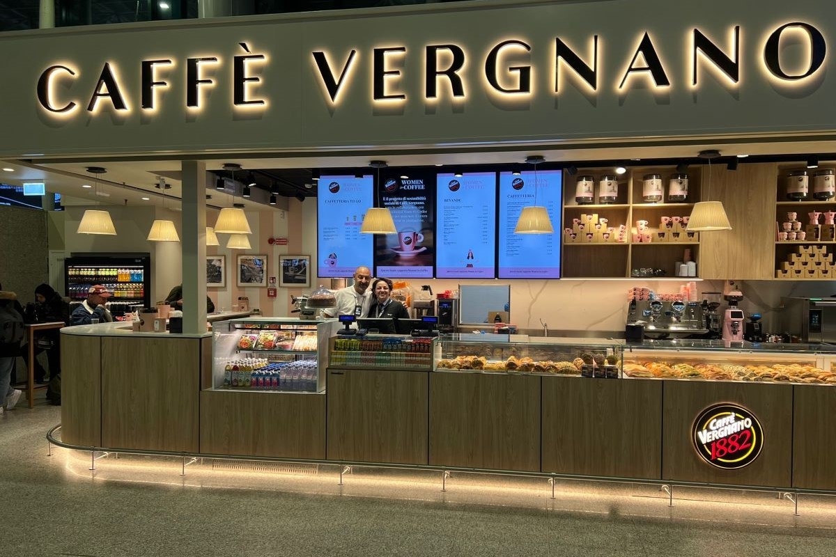 Caffè Vergnano a Fiumicino. Bar con insegna luminosa, bancone con dolci e bevande. Women in Coffee.