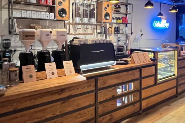 Interno del locale Costadoro a Londra. Macchine da caffè, arredo in legno e insegna al neon.