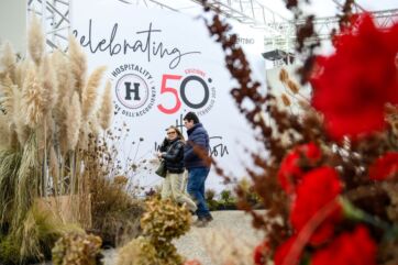 Evento Hospitality 2026: persone, relazioni e futuro del settore. Stand fiera con logo e decorazioni floreali.