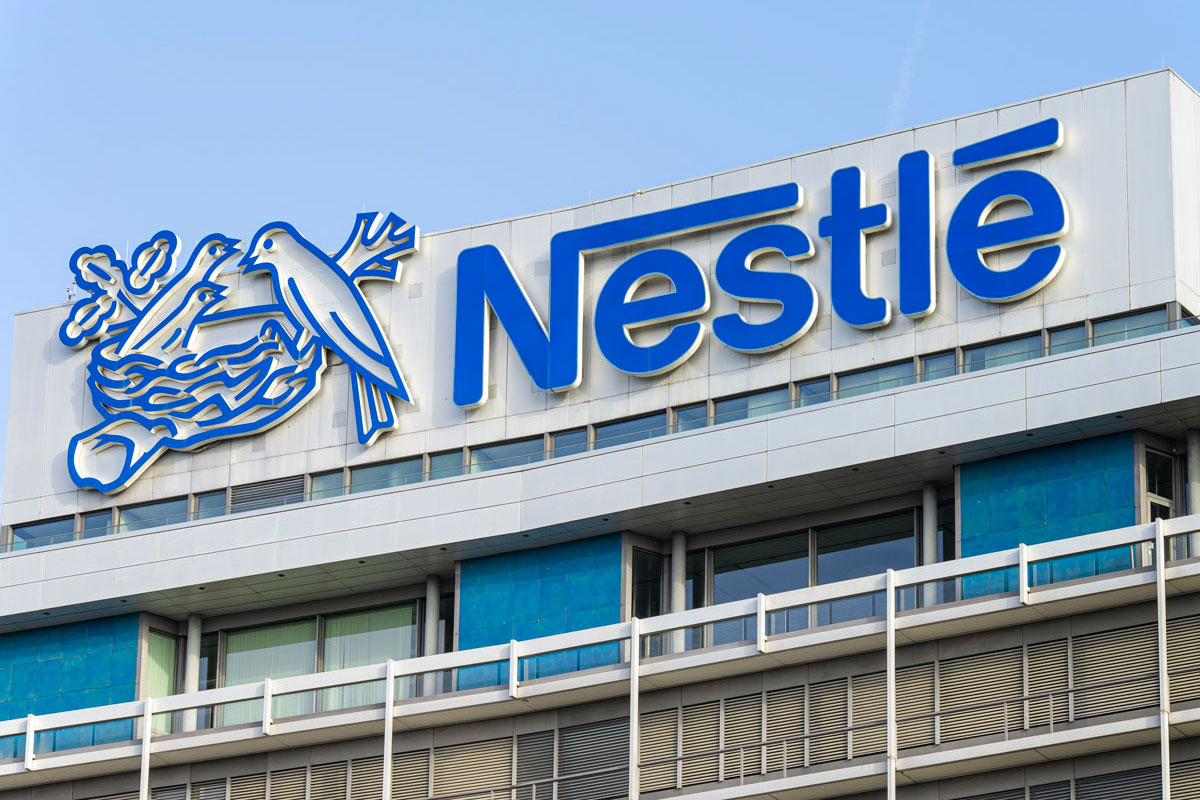 Logo Nestlé su edificio. Icona nido con uccelli, marchio aziendale blu.