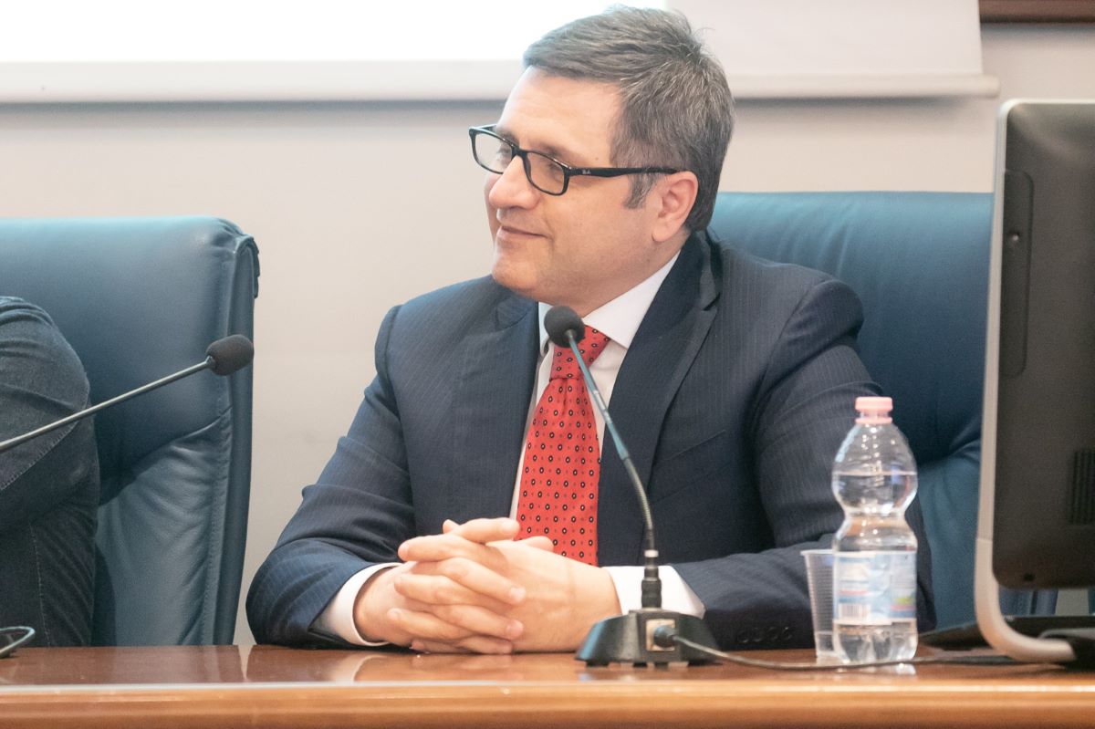 Uomo in giacca e cravatta rossa a conferenza. Bozza automatica.