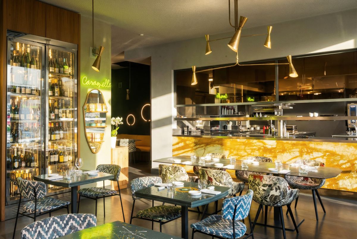 Interno del locale 142 Milano: tavoli apparecchiati, cucina a vista, illuminazione di design. Ristorante e bistrot.