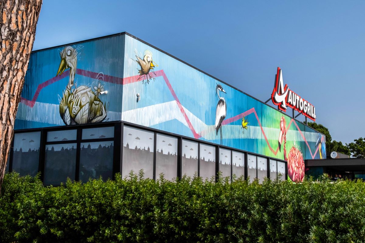 Autogrill Arezzo con murales Urban Art. Design con uccelli e skyline.