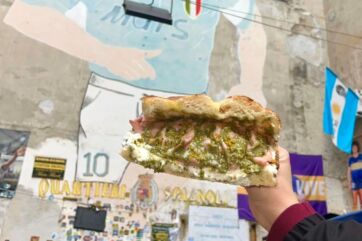 Panino di All'Antico Vinaio a Napoli. Street food napoletano con murales di Maradona sullo sfondo.