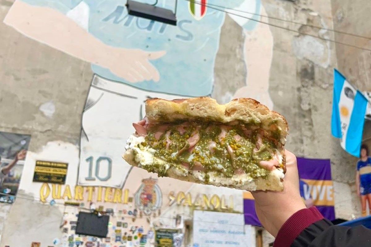 Panino di All'Antico Vinaio a Napoli. Street food napoletano con murales di Maradona sullo sfondo.