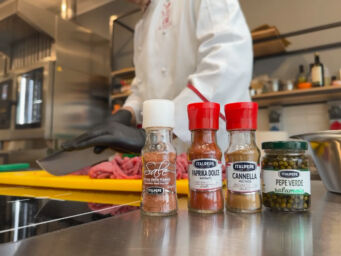 Italpepe e Meatschool: spezie e formazione carni. Chef prepara carne con sale rosso, paprika, cannella e pepe verde.