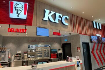 Interno del ristorante KFC a Forlì. Logo KFC, servizio delivery e area ritiro ordini. Pollo fritto Kentucky.