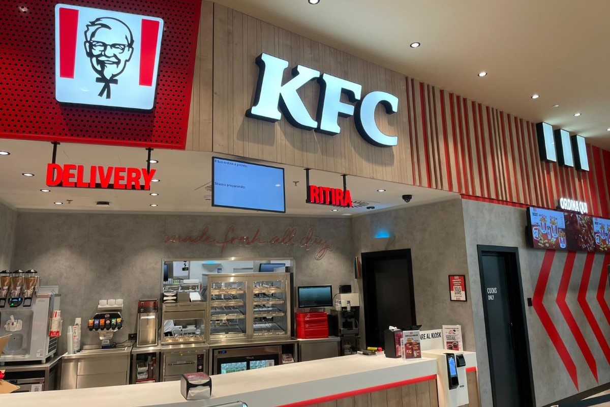 Interno del ristorante KFC a Forlì. Logo KFC, servizio delivery e area ritiro ordini. Pollo fritto Kentucky.