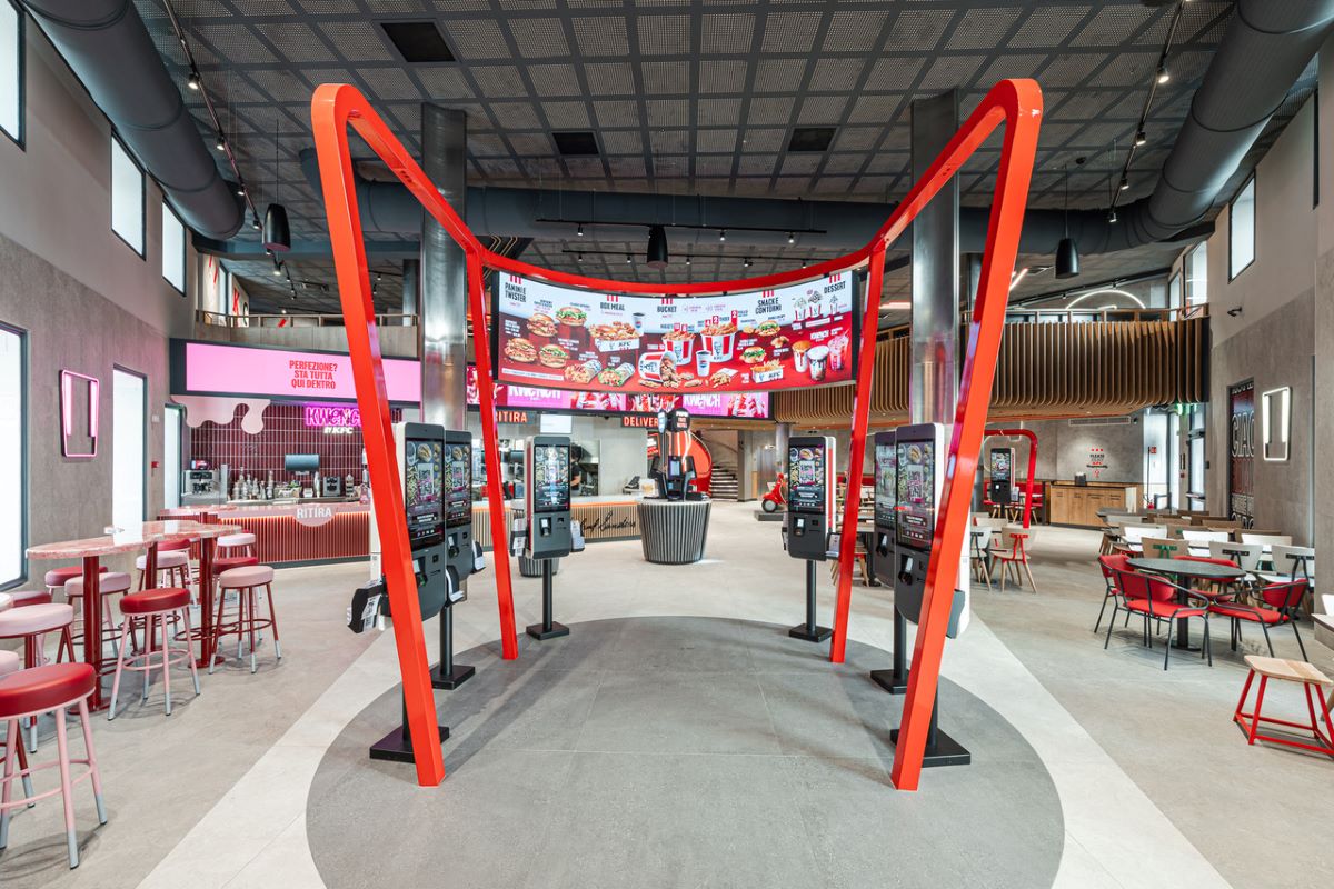 Interni del ristorante KFC Roma: schermi digitali per ordinare, design moderno e tavoli. KFC Italia.