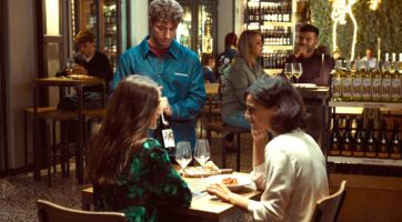 Clienti Signorvino degustano vino al calice. Ambiente accogliente, focus sul consumo di vino e socializzazione.