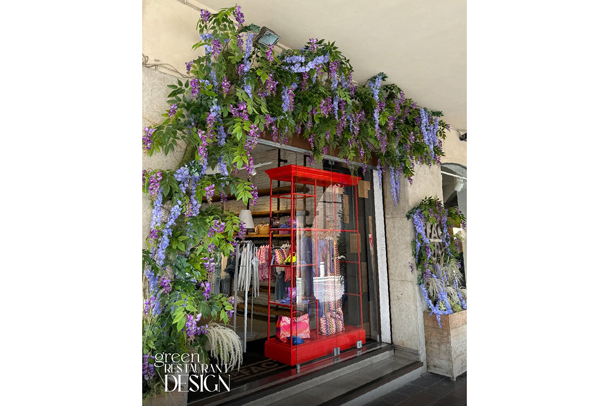 Design ristorante green: vetrina fiorita con glicine viola e struttura rossa. Arredamento floreale per ristoranti.
