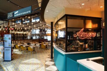 Amore, ristorante all'aeroporto di Roma Fiumicino. Design moderno, illuminazione calda, tavoli e sedie colorate.