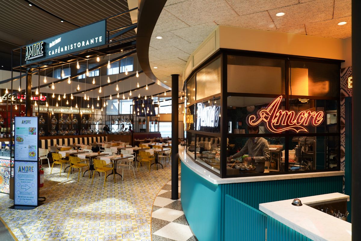 Amore, ristorante all'aeroporto di Roma Fiumicino. Design moderno, illuminazione calda, tavoli e sedie colorate.