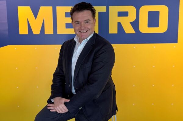 Marco Celenta, nuovo Direttore Offer Management Metro Italia. Ritratto su sfondo giallo/blu Metro.