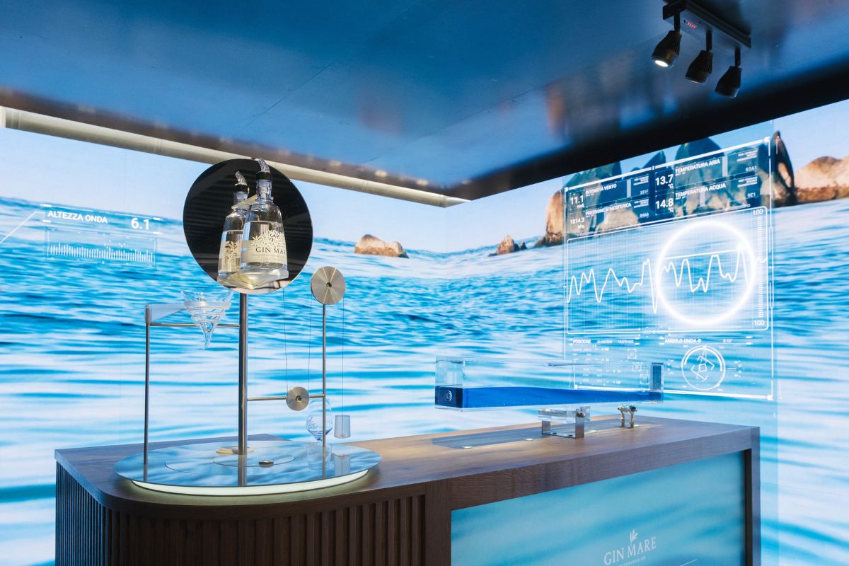 Gin Mare: esperienza gin tonic immersiva. Bottiglie di gin e mare sullo sfondo per un'atmosfera unica. #GinMare #Maretender