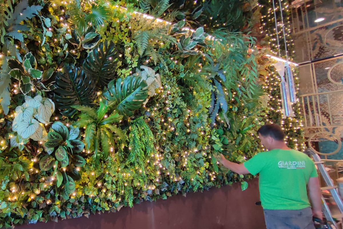 Design ristorante green: parete verticale con piante, luci e giardiniere. Emozione verde per il tuo business.