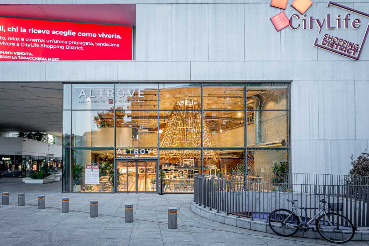 Ingresso Altrove, bistrot Il Viaggiator Goloso a CityLife Milano. Design moderno, vetrine ampie. Bicicletta parcheggiata.