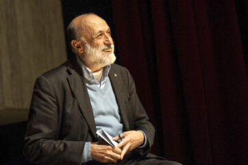 Ritratto di Carlo Petrini, fondatore di Slow Food. Sorriso, barba bianca e sguardo rivolto verso l'alto.