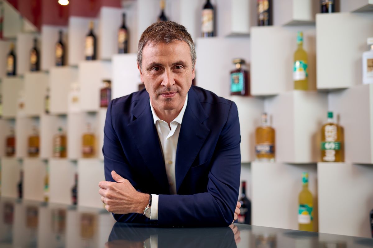Marco Ferrari, CEO Disaronno Group. Ritratto aziendale con liquori sullo sfondo.