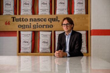 Claudio Baitelli, Amministratore Delegato di Alice Pizza, davanti a scaffali con sacchi di farina del brand.