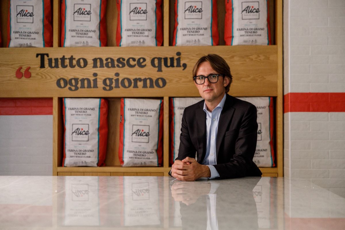 Claudio Baitelli, Amministratore Delegato di Alice Pizza, davanti a scaffali con sacchi di farina del brand.
