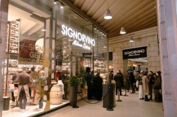 Vetrina del negozio Signorvino a Milano Duomo con clienti in fila e interni eleganti pieni di bottiglie di vino.