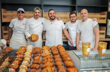 Team di Sfoorna, micro forno artigianale Carpe Diem in Abruzzo, posa sorridente davanti a un banco di pane e cornetti.