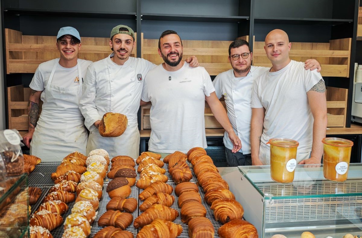 Team di Sfoorna, micro forno artigianale Carpe Diem in Abruzzo, posa sorridente davanti a un banco di pane e cornetti.