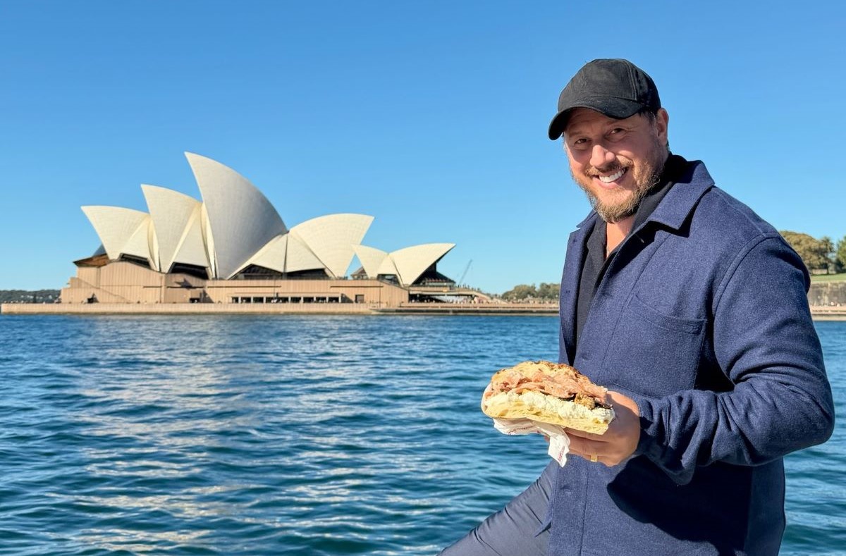 Tommaso Mazzanti di All'Antico Vinaio con una schiacciata davanti alla Sydney Opera House in Australia.