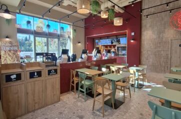 Interni moderni del punto vendita La Piadineria presso Manifattura Tabacchi con tavoli, sedie e area ricette regionali.