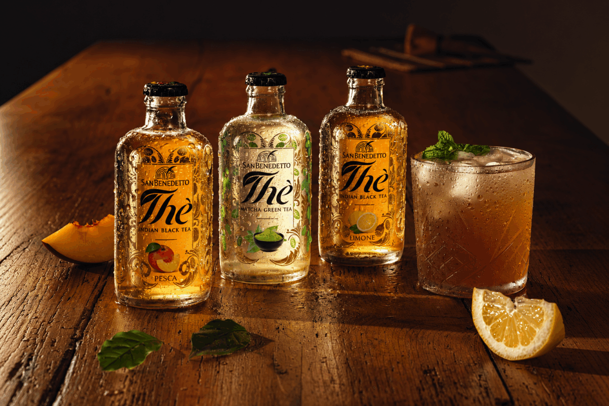 Tre bottiglie di San Benedetto Premium Tea: Pesca, Matcha e Limone con un bicchiere di tè freddo su tavolo in legno.