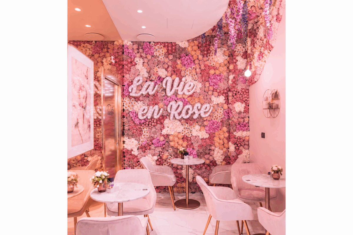 Green Restaurant Design: interno di locale con parete floreale rosa, tavolini in marmo e sedie in velluto rosa.