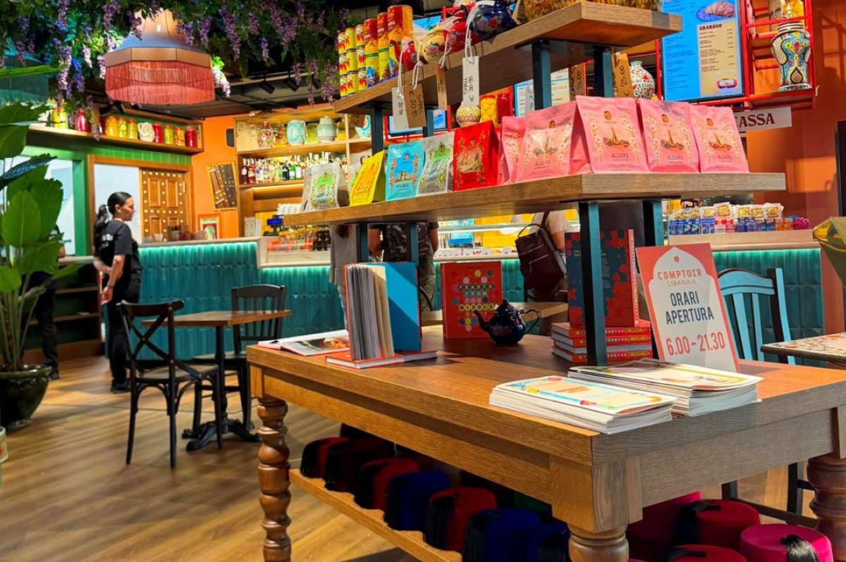 Interno del ristorante Comptoir Libanais a Roma Termini con scaffali di prodotti tipici, libri e orari di apertura.