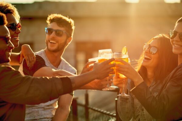 Gruppo di amici brinda con cocktail al tramonto durante l'evento Heineken Together Lab, atmosfera gioiosa e conviviale.