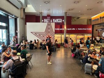 Nuovo punto vendita Pret A Manger all'interno della stazione Roma Termini con clienti ai tavoli e insegna luminosa.