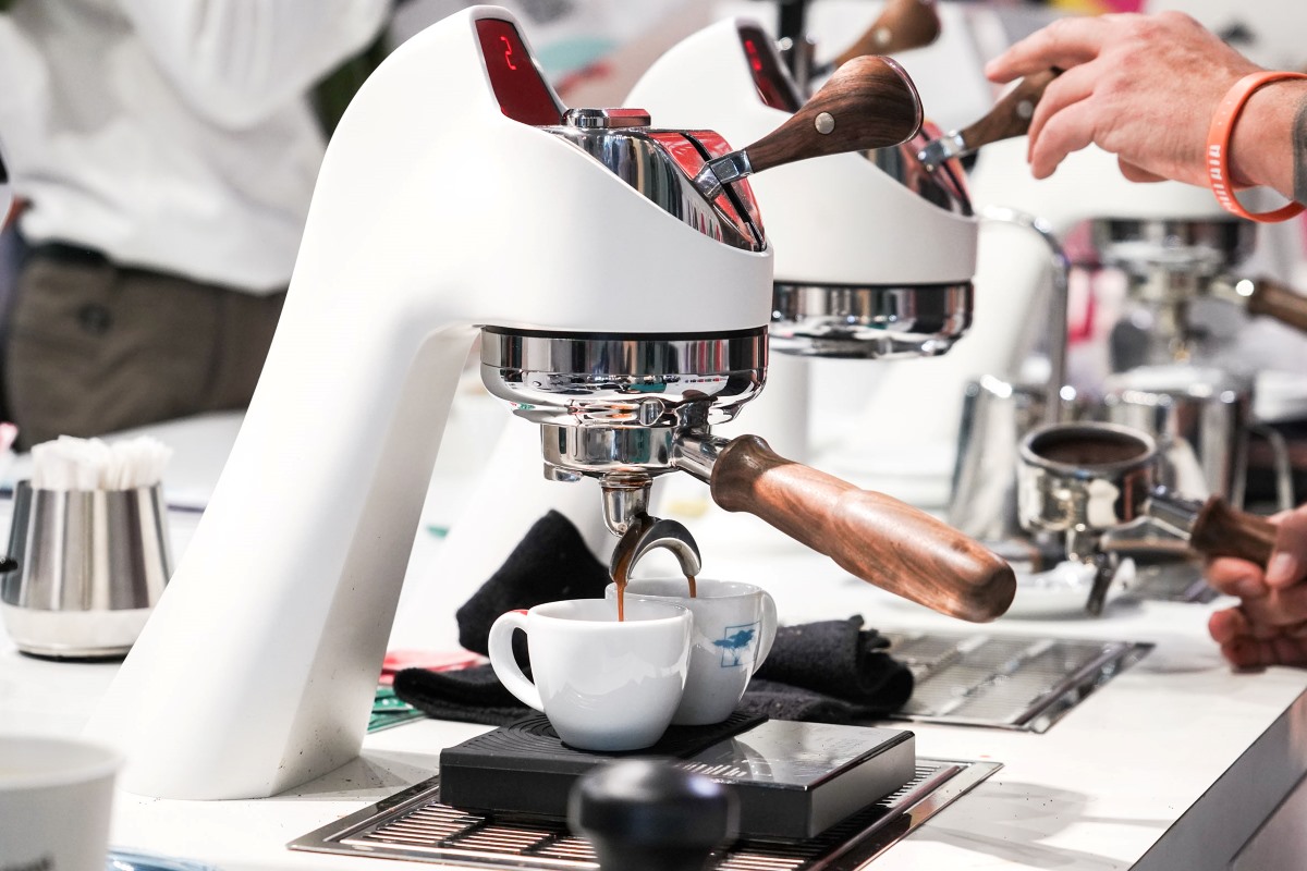 Macchina professionale per caffè espresso con tazza bianca in primo piano, simbolo di consumo consapevole e sostenibilità